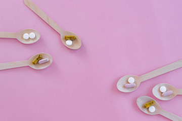 Pills in the spoons. Concepts - what we eat, hidden ingredients, addictions. Pink background and space for text.