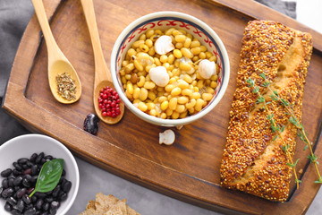 Bowl with boiled beans and bread on table