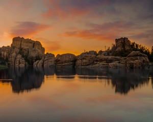 Beautiful shot of a reflection of a cliff on body of water during golden hour - Powered by Adobe