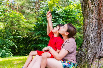 mom and son having fun under a tree in the summer