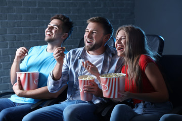 Friends with popcorn watching movie in cinema
