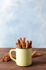 Mug with aromatic cinnamon sticks on wooden table