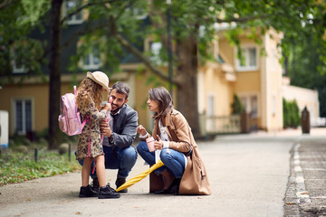 parents saying goodbye to their little child near school