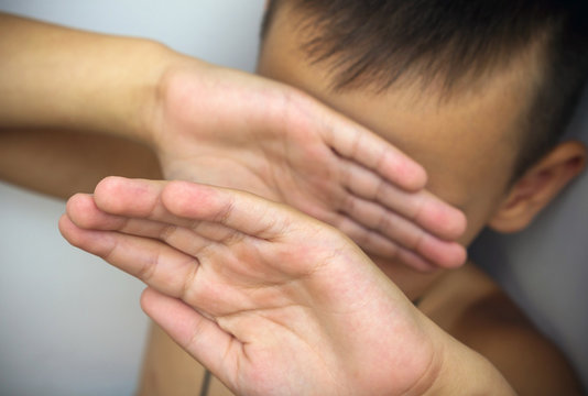 Violence in family, child abuse or bullying. The child covers his face with his hands, protecting himself from beating. Concept image, selective focus.