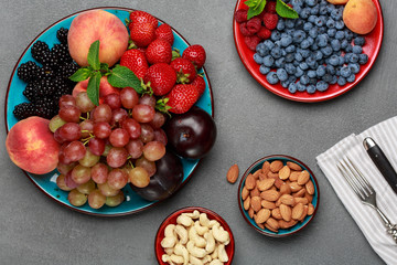 Seasonal fruits and nuts on concrete table, fresh ingredients for lunch. Healthy food concept. Top view.