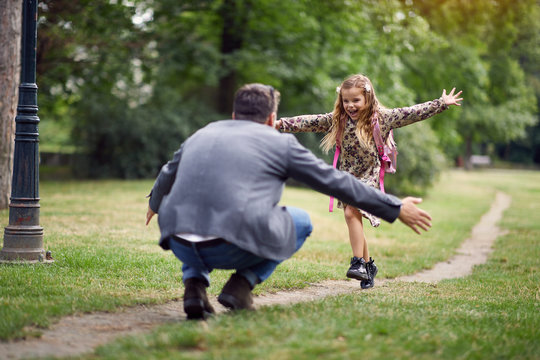 schoolgirl running to dad to give him a hug