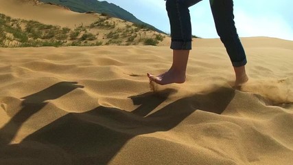 A woman runs along the sand in the desert. A girl runs barefoot on a sand dune in the sand. Slow motion