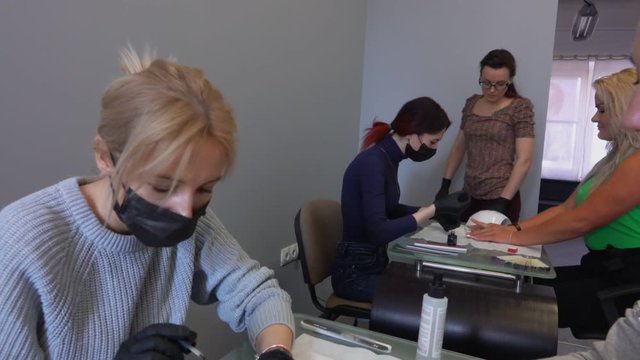 Panorama of manicure retraining courses. Manicure teacher observes the work of his students
