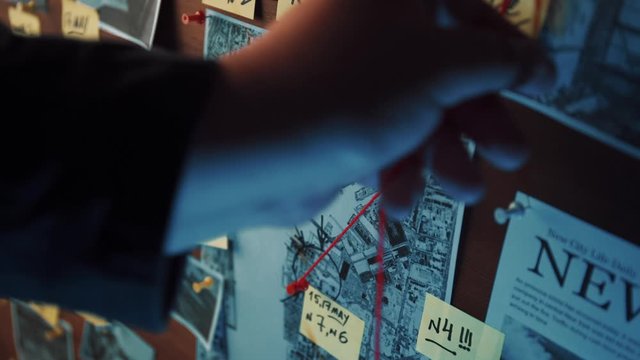 Detective board with photos of suspected criminals, crime scenes and evidence with red threads