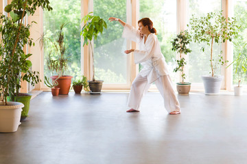 Young Woman praticing tai chi chuan in the gym. Chinese management skill Qi's energy.