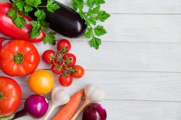 Tomatoes, peppers, eggplants and other vegetables on a white wooden table