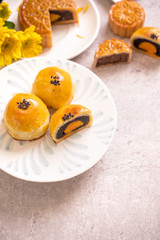Mid-Autumn Festival traditional food concept - Beautiful cut moon cake on blue pattern plate on white background with flower, close up, copy space