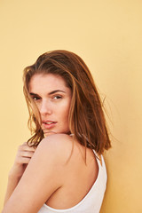 Fototapeta premium Beautiful brown eyed brunette against yellow background