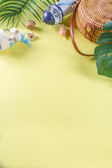 Summer vacation background. Tropical leaves, wicker bag, summer accessories and decorations. Yellow background top view flat lay