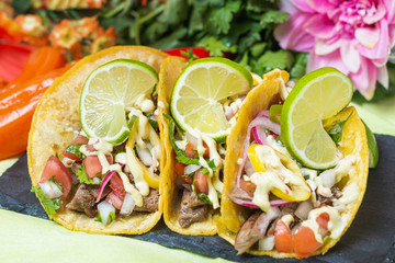 Tacos crowned with lime surrounded by flowers close up