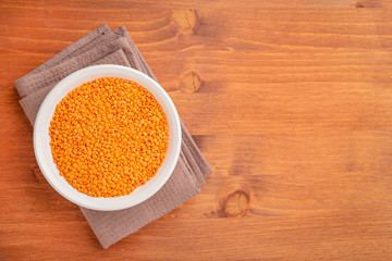 Bowl of red lentils on wooden background