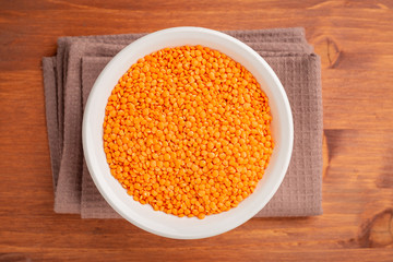Bowl of red lentils on wooden background