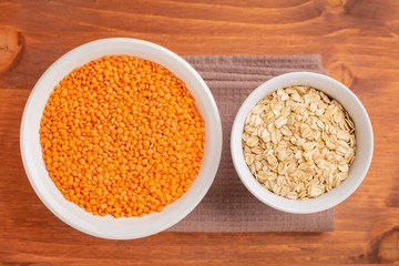 Raw red lentils, oak flakes in white bowls.