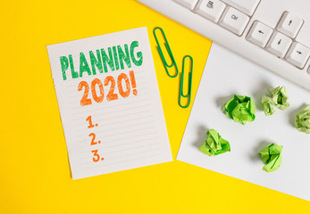 Conceptual hand writing showing Planning 2020. Concept meaning process of making plans for something next year Flat lay with copy space white paper with paper clips on the table