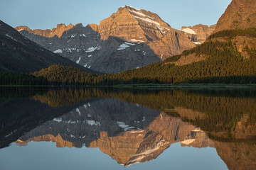 Mountains reflect in the morning light on Swiftcurrent Lake, Glacier National Park, Montana
