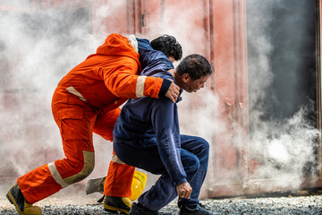Fototapeta na wymiar Medium shot of firefighter in fire suit on safety rescue duty help a man inside burning premises by first aid emergency. Safety, rescue and health care concept.