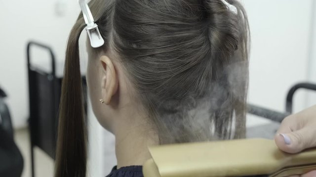 hairdresser makes hair lamination in a beauty salon for a girl with brunette hair