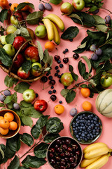 Flat-lay of fresh fruits and berries on pink background