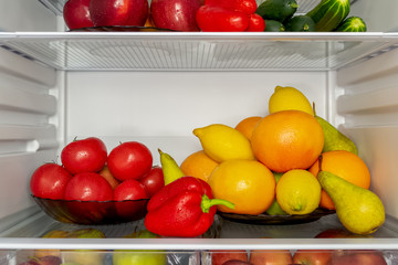 Refrigerator filled with useful products. Vegetables and fruits. Cucumbers, tomatoes and peppers, apples, pears, lemons, oranges and grapefruits. Diet, vegetarianism, weight loss concept