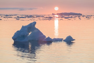 Arctic nature landscape with icebergs in Greenland icefjord with midnight sun sunset / sunrise in...