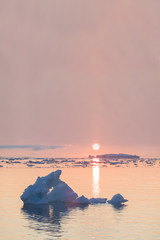 Arctic nature landscape with icebergs in Greenland icefjord with midnight sun sunset / sunrise in...