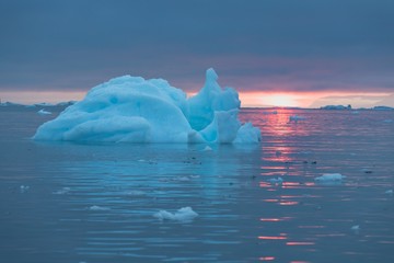 Arctic nature landscape with icebergs in Greenland icefjord with midnight sun sunset / sunrise in...