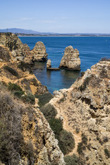 Vacation in Algarve - View of colourful cliffs off Ponta da Piedade headland and cliffs rising from the turquoise waters of the sea. Shore in distance