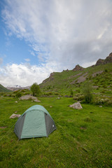 Touristic tent on grass field mountains valley