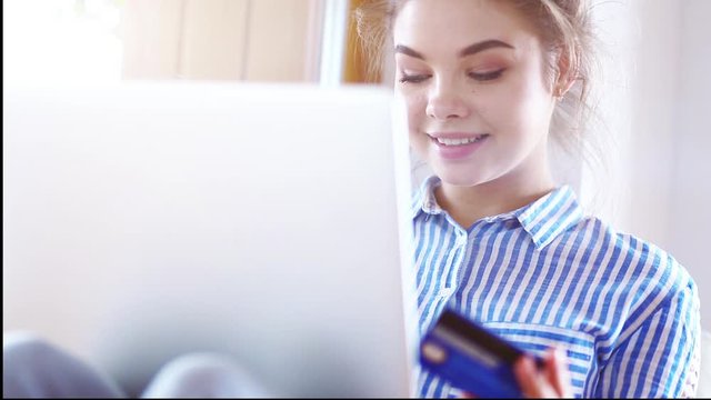 Girll is making online payment. Girl holding bank card using modern laptop