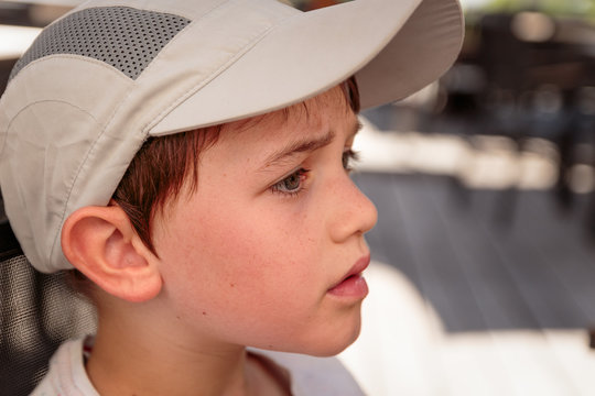 Portrait of a cute little 8 year old boy outdoors wearing a gray baseball hat