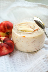 selective focus, still life, Breakfast. berry light peach yogurt with cereals in a glass jar with peach slices on a white tablecloth