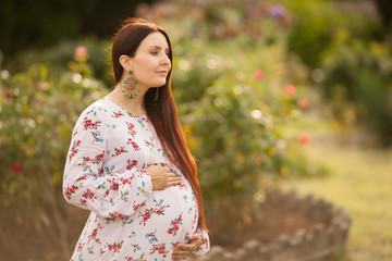 beautiful pregnant woman in dress walking in Park