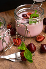 selective focus, still life, Breakfast. cherry pink yogurt in a glass jar with ripe cherries and green mint leaves