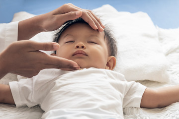 Mom is using her hands to massage Under the chin of child for to open the airway, concept to health care for child and relax.