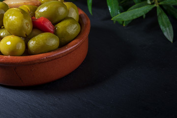 Clay pot with artisan olives with red peppers and garlic. Includes leaves of the olive tree.Space to insert your text here.