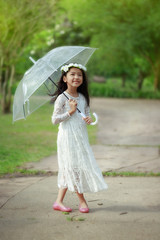 Little Asian girl holding clear umbrella and smiling with happiness select focus shallow depth of field