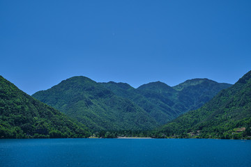 Panoramic view of Lake Ledro in the north of Italy In the Alps. Blue lake, in the background green mountains, blue sky.