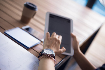 Women's hands with neat manicure and large wristwatch, work with gadgets, tablet, smartphone,...