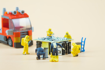 Tiny figures of chemical team in hazmat suits examining