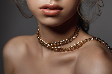 Lips and neck of a woman close-up, large gold chain decoration on the neck
