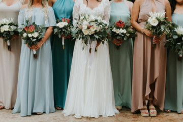 Bride and bridesmaids holding wedding bouquets, pastel blue and pink color dresses