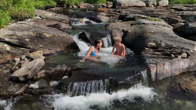 A mother and her son swimming in a mountain creek in northern Sweden