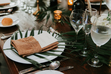 wedding reception table setting, wedding menu card on plate, wrapped in burlap and twine with palm leaf