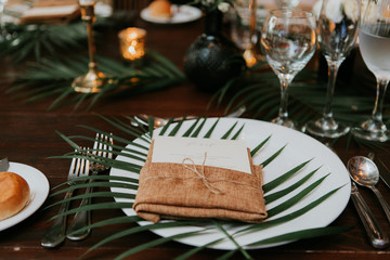 wedding reception table setting, wedding menu card on plate, wrapped in burlap and twine with palm leaf