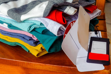 New colored knitted T-shirts with tags and price tags are stacked on a chair.